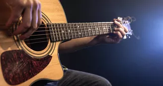 Close-up shot of guitarist playing acoustic guitar, copy space.